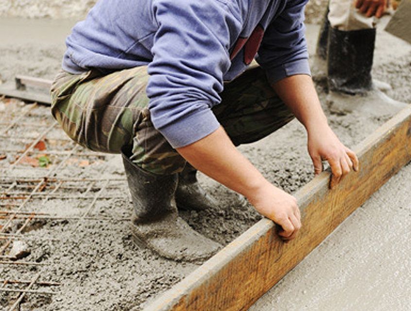Maçon en train de lisser une dalle en béton